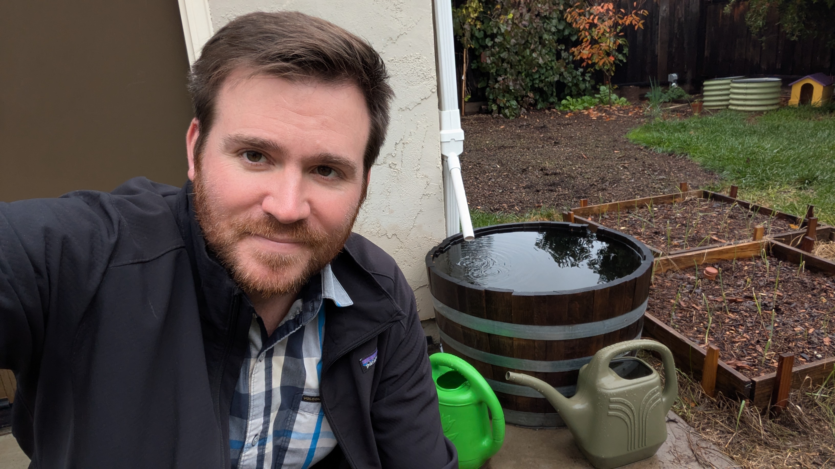 A picture of me and my very basic rain barrel in my backyard.